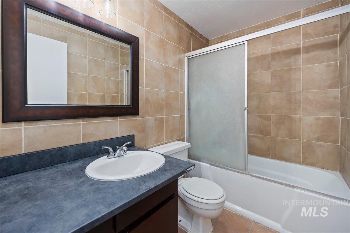 259 Pheasant Road, Unit 84 Twin Falls, ID 83301 - Photo 15 of 25 Bathroom featuring a full vanity with an integrated sink, a large framed mirror, and a bathtub with a sliding glass enclosure