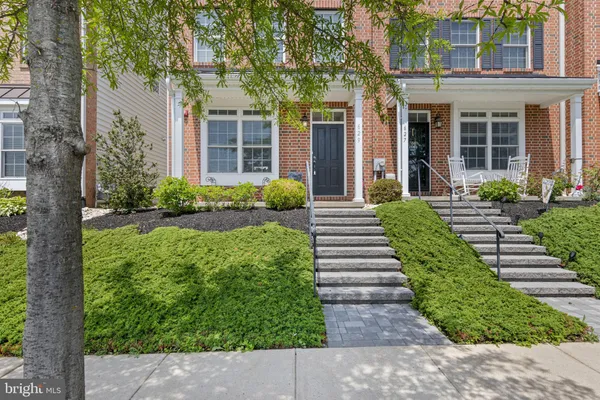a view of a house with brick walls plants and large tree