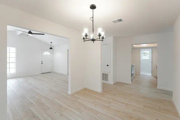 a view of a livingroom with wooden floor staircase and a chandelier