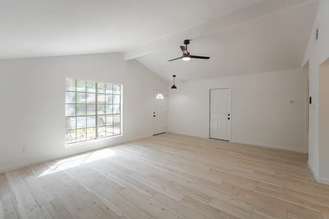 a view of an empty room with a window and wooden floor