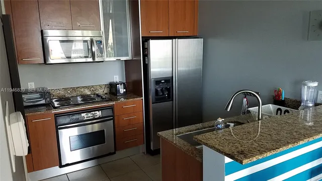 a kitchen with granite countertop a stove top oven microwave and refrigerator