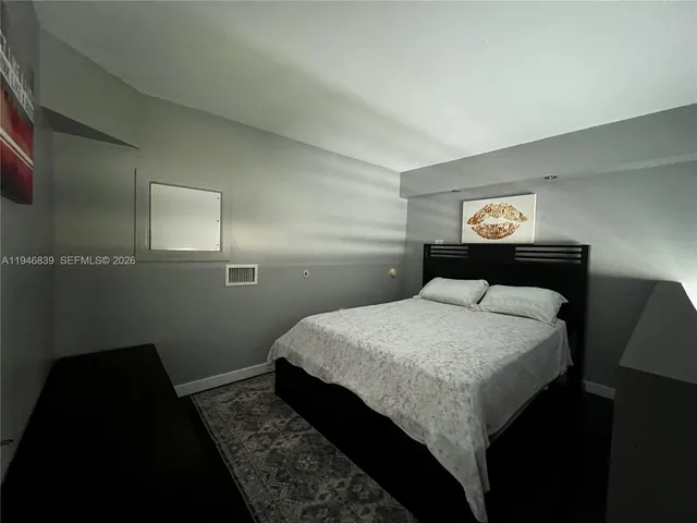 a bedroom with a bed and a lamp on dresser