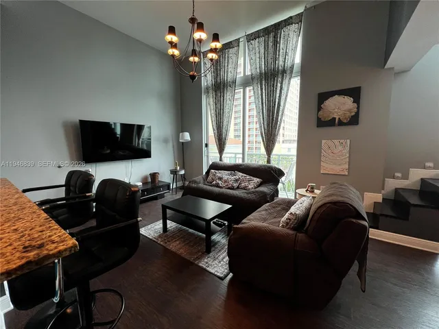 a living room with furniture a chandelier and a flat screen tv