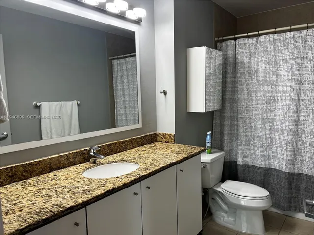 a bathroom with a granite countertop sink toilet and shower