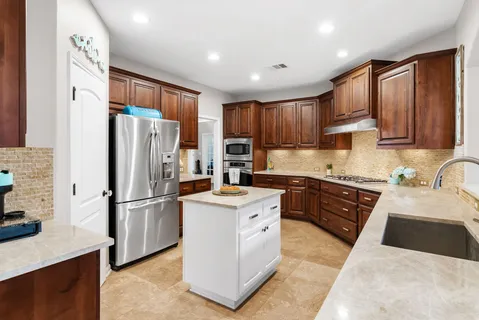 a kitchen with stainless steel appliances granite countertop a refrigerator stove sink and cabinets