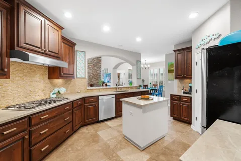 a kitchen with stainless steel appliances granite countertop a stove top oven a sink dishwasher a refrigerator and cabinets with wooden floor