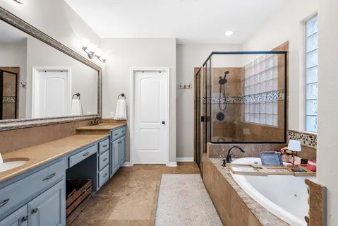 a spacious bathroom with a double vanity sink large mirror and a bathtub