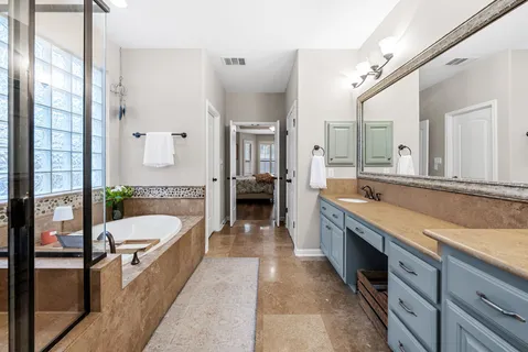 a large spacious bathroom with a granite countertop tub double vanity and mirrors