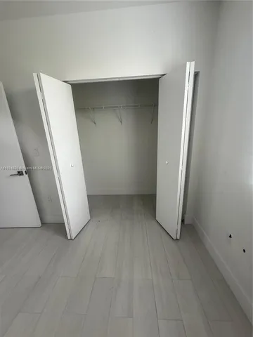 an empty room with wooden floor and entrance