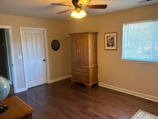 an empty room with wooden floor a ceiling fan and windows