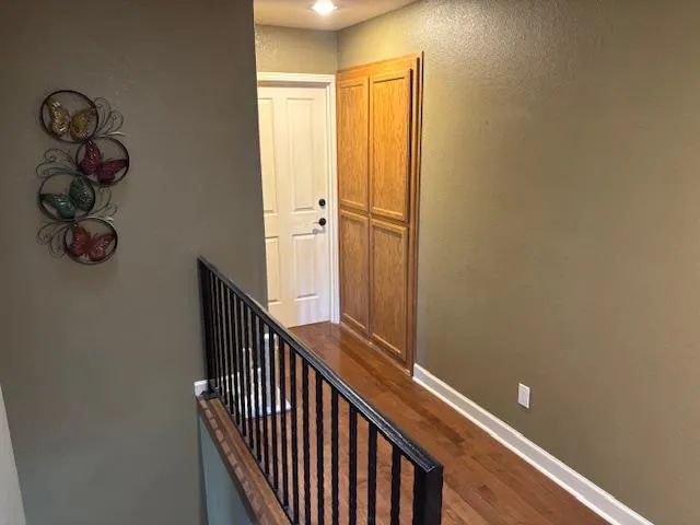 a view of a hallway with wooden floor and stairs