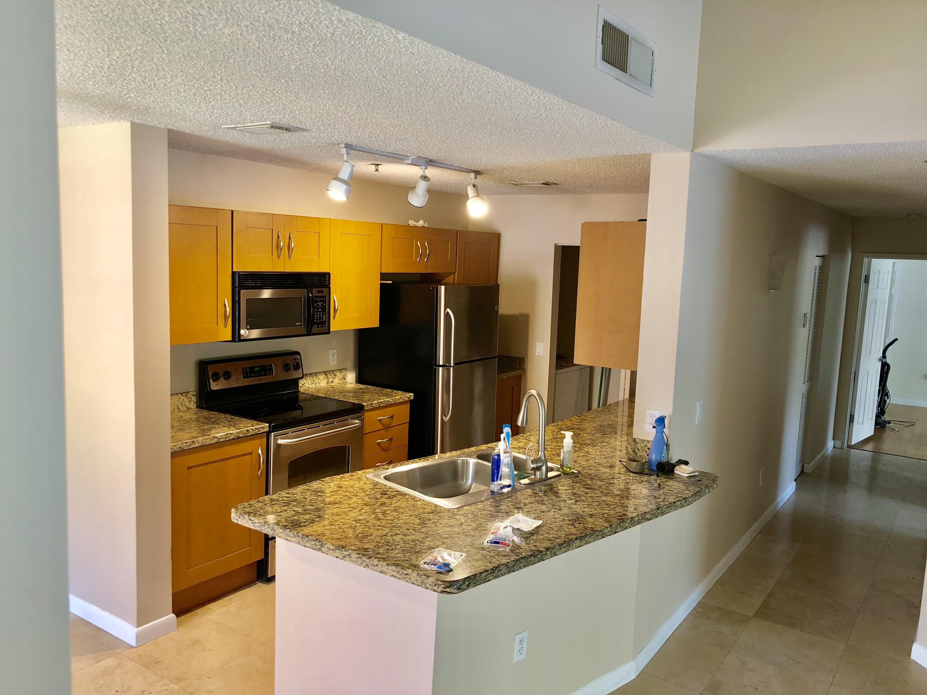 3133 Clint Moore Road, Unit 201 Boca Raton, FL 33496 - Photo 4 of 15 a kitchen with kitchen island granite countertop a sink stove and refrigerator
