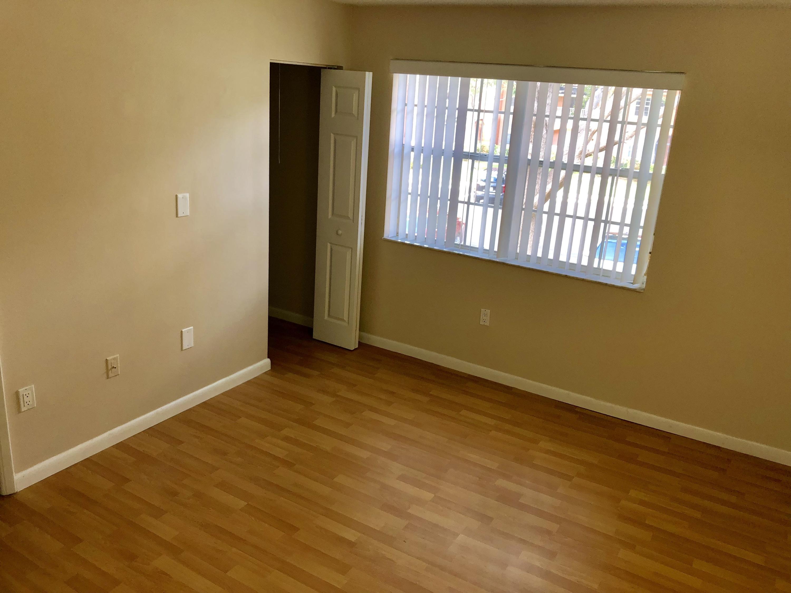 3133 Clint Moore Road, Unit 201 Boca Raton, FL 33496 - Photo 8 of 15 a view of an empty room with wooden floor and a window