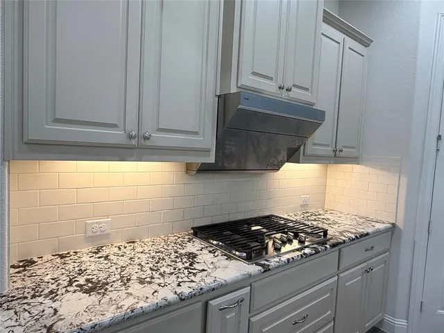 a kitchen with granite countertop a stove and a wooden cabinets