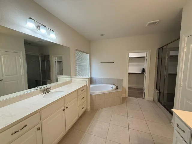 a spacious bathroom with a double vanity sink a mirror and a bathtub