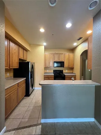 a close view of a refrigerator in kitchen and an empty room with wooden floor