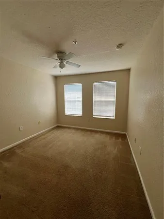 an empty room with a window and a ceiling fan