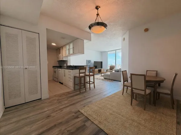 a view of a dining room and livingroom with furniture wooden floor a chandelier
