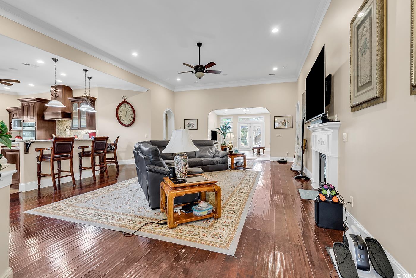 487 Trestle Way Conway, SC 29526 - Photo 5 of 40 Living area with ceiling fan, arched walkways, a fireplace with raised hearth, dark wood-type flooring, and recessed lighting
