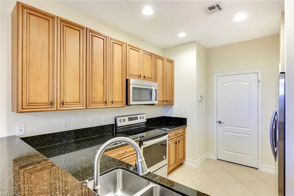 a kitchen with granite countertop a sink a stove and cabinets
