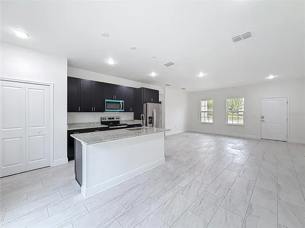 a view of kitchen with kitchen island granite countertop a stove top oven a sink and dishwasher with wooden floor