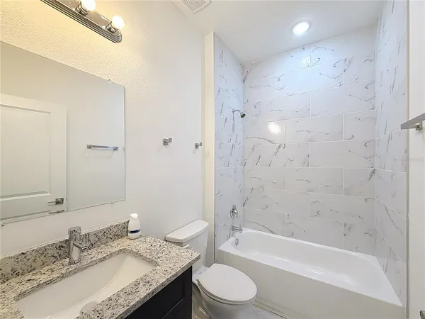 a bathroom with a granite countertop sink a toilet and bathtub