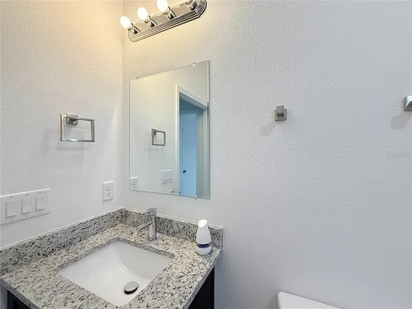 a bathroom with a granite countertop sink and a mirror
