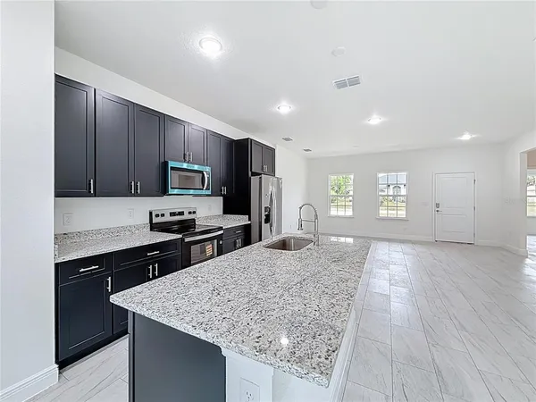 a kitchen with granite countertop cabinets appliances and a counter space