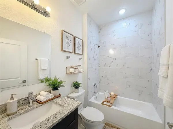 a bathroom with a granite countertop sink a toilet and shower