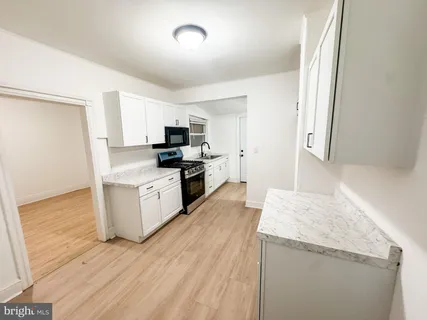 a kitchen with granite countertop wooden floors and white stainless steel appliances