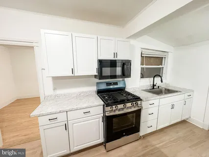 a kitchen with granite countertop a sink stove and microwave