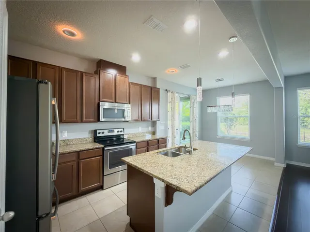 a kitchen with kitchen island granite countertop wooden cabinets and stainless steel appliances