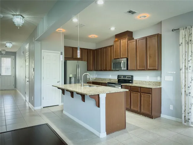 a kitchen with stainless steel appliances granite countertop a refrigerator a sink and a stove