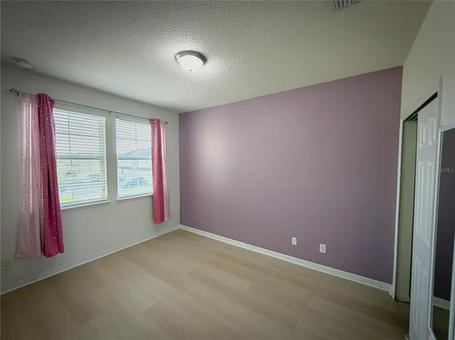 a view of an empty room with window and bathroom
