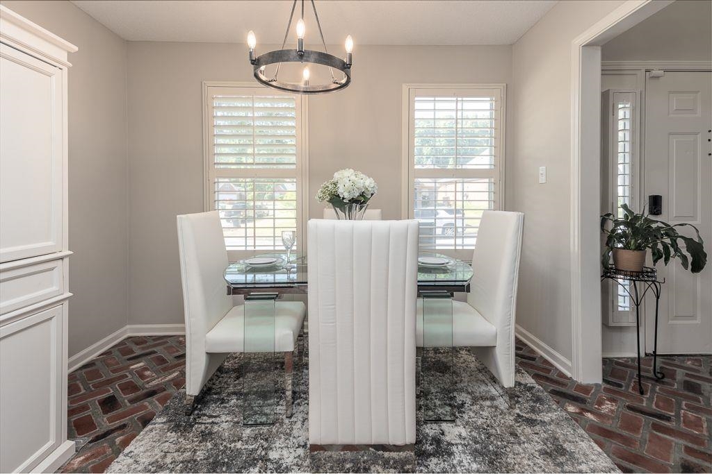 9768 Riggin Drive Memphis, TN 38002 - Photo 9 of 32 Dining area featuring brick flooring, plantation shutters, and a chandelier