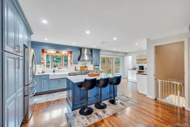 a living room with stainless steel appliances granite countertop furniture wooden floor and a kitchen view