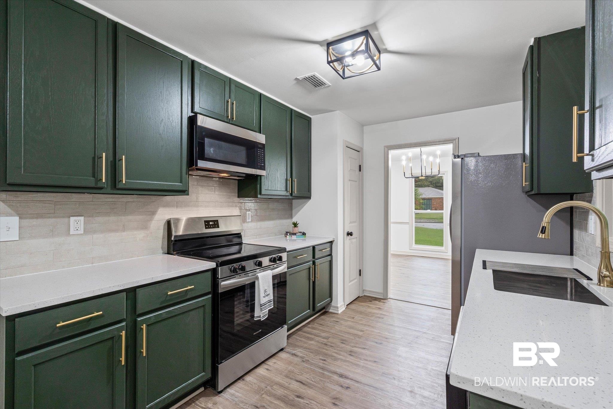3655 Claridge Road South Mobile, AL 36608 - Photo 12 of 32 Kitchen with green cabinets, decorative backsplash, appliances with stainless steel finishes, and light wood-style floors