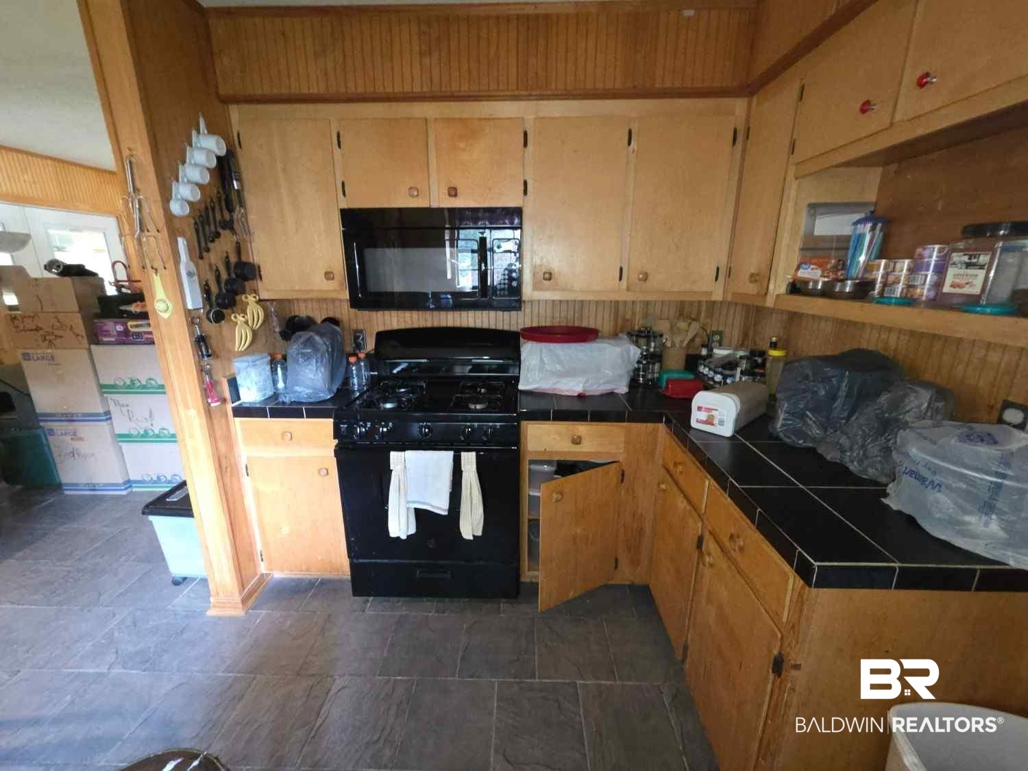 5120 West Celtic Drive Mobile, AL 36619 - Photo 9 of 27 Kitchen featuring tile countertops, black appliances, and wood walls