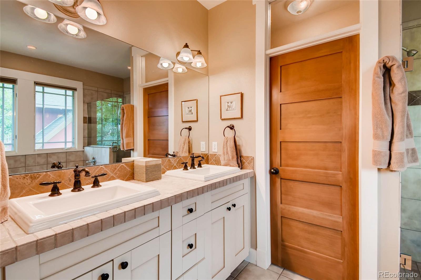 11770 Perry Street Westminster, CO 80031 - Photo 17 of 28 a bathroom with a double vanity sink a mirror and a bathtub
