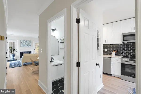 a kitchen with stainless steel appliances a refrigerator a stove a sink and white cabinets with wooden floor