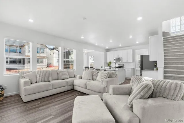 a living room with furniture kitchen view and a large window