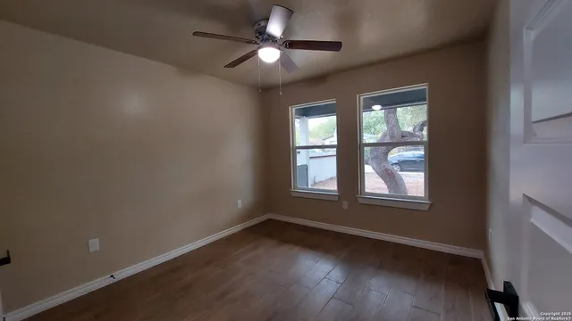 an empty room with wooden floor and windows