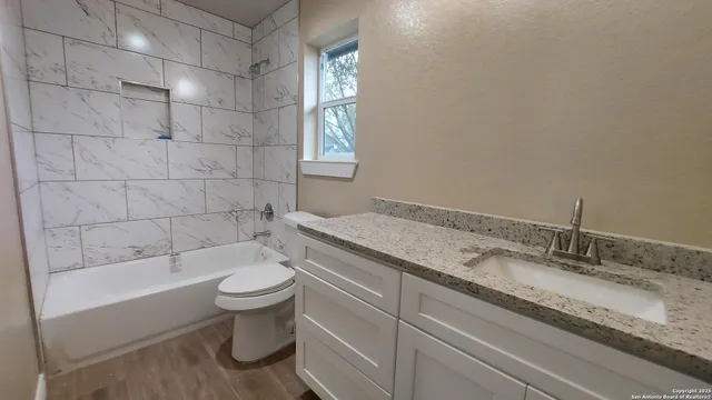 a bathroom with a granite countertop sink a toilet and bathtub
