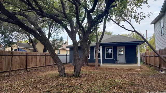 a view of a house with a tree and wooden fence