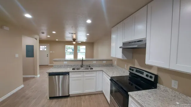 a kitchen with granite countertop a sink a stove and cabinets