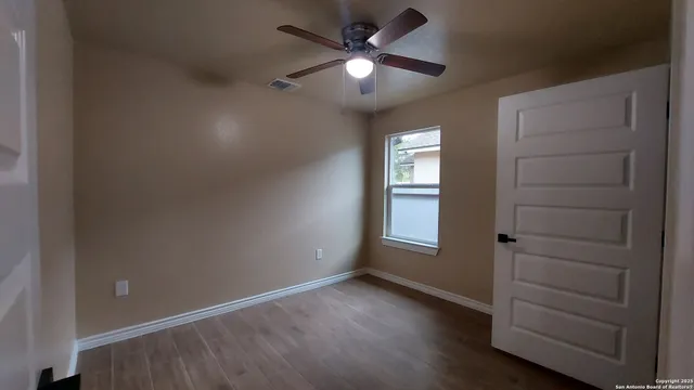an empty room with windows and fan