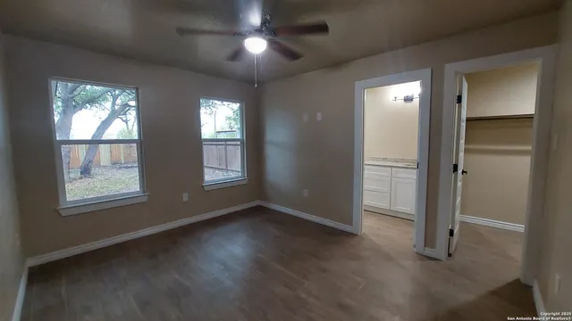 an empty room with wooden floor cabinet and windows