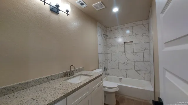 a bathroom with a granite countertop sink a toilet and bathtub