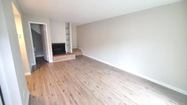 an empty room with wooden floor and fireplace
