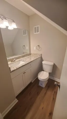 a bathroom with a granite countertop toilet sink mirror and vanity